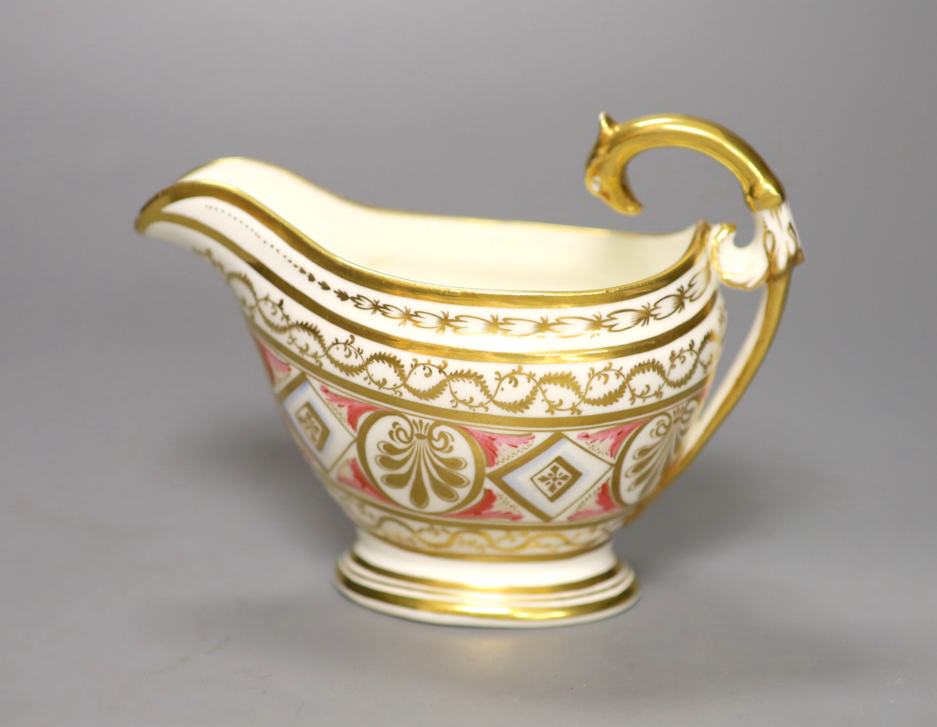 A rare English porcelain sauceboat, with swan neck handle gilded with alternating oval and diamond shaped panels and puce festoons,